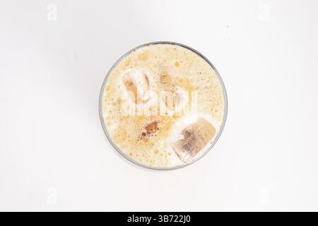 caffè ghiacciato con crema e cubetti di ghiaccio servito in alto vetro trasparente con la parte superiore schiumosa fotografata su sfondo bianco. Foto di alta qualità Foto Stock