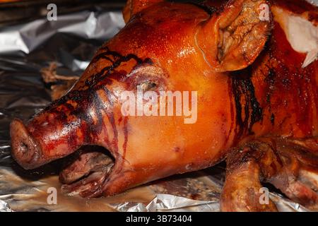 Un maiale arrosto intero, da vicino, giace sul tavolo ed è pronto per essere mangiato. Foto Stock