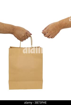 Un sacchetto di carta marrone a due mani che simboleggia la transazione o la consegna. l'immagine cattura il momento del trasferimento, evidenziando semplicità e funzionalità Foto Stock
