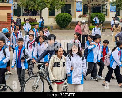 Gli studenti di una scuola media a Thanh Hoa, Vietnam, il 18 marzo 2025 lasciano la scuola dopo le lezioni. Gli alunni sono vestiti con uniformi bianche e blu. Foto Stock
