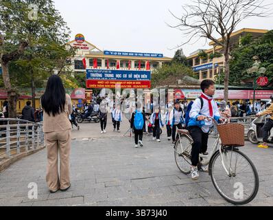 Gli studenti di una scuola media di Thanh Hoa, Vietnam, lasciano le loro classi dopo le lezioni il 18 marzo 2025, l'ingresso della scuola è abbellito da un divieto Foto Stock