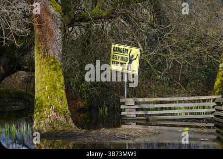 Cartello di pericolo "Deep Mud Keep Out" accanto allo stagno. Foto Stock