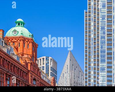 Londra, Regno Unito - 28 aprile 2025: Una giustapposizione di stili architettonici con uno storico edificio in mattoni rossi con una cupola verde e un moder Foto Stock