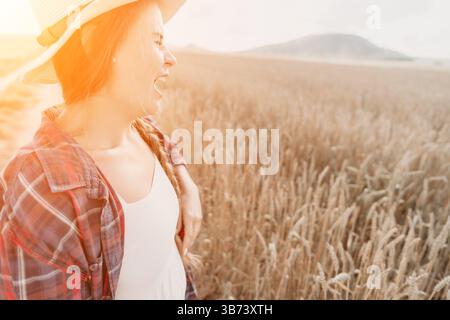 Donna campo di grano. Agronomo, agricoltore donna che controlla i picchi d'orzo maturo dorato nel campo coltivato. Primo piano della mano femminile sulla piantagione in agricoltura Foto Stock
