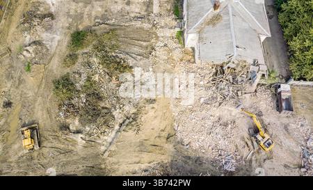 cantiere di demolizione con macchine pesanti in funzione e un mucchio di detriti di edifici distrutti. vista aerea con drone. Foto Stock
