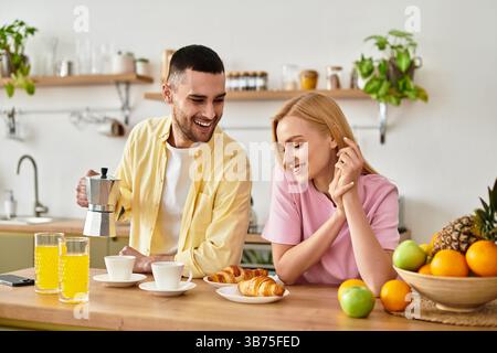 Una coppia allegra condivide un delizioso momento di colazione mentre ride e si gode la luce del mattino. Foto Stock