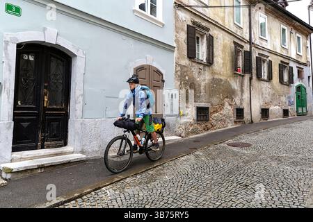 Adolescente in un viaggio in bicicletta per la Slovenia, ciclista in bicicletta sulle strade di ciottoli nella pittoresca parte vecchia di Lubiana, Slovenia Foto Stock