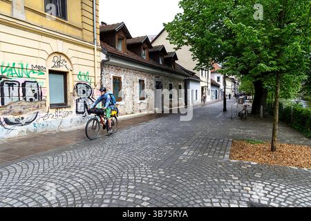 Adolescente in un viaggio in bicicletta per la Slovenia, ciclista in bicicletta sulle strade di ciottoli nella pittoresca parte vecchia di Lubiana, Slovenia Foto Stock