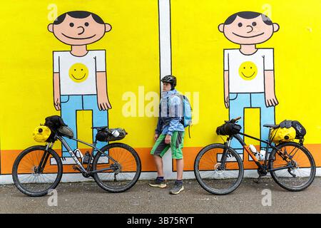 Adolescente in un viaggio in bicicletta in Slovenia, ciclista che si ferma davanti ai pittoreschi murali nella parte vecchia di Lubiana, Slovenia Foto Stock