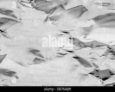 Primo piano astratto di lamina d'argento riflettente intensamente deturpata (simile a carta e alluminio) Foto Stock
