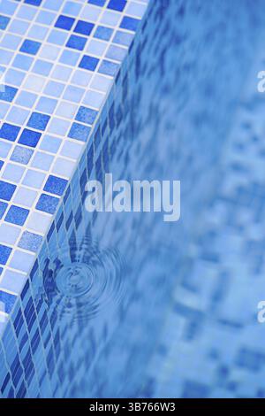 L'acqua si macchia da una goccia ai gradini con un mosaico blu in piscina. Foto Stock