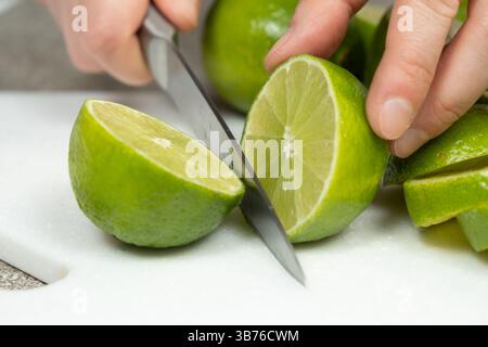 Tagliando a metà il lime fresco con un coltello da cucina. Foto Stock
