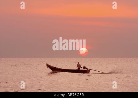 Un tranquillo tramonto sull'oceano caratterizzato da un pescatore che pagaiava con grazia in canoa, catturando la bellezza serena, Un tramonto sereno proietta un caldo bagliore su t Foto Stock