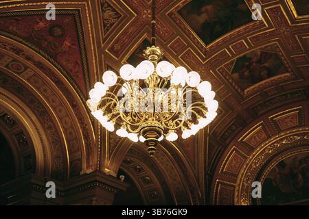 Elegante lampadario interno con lampadine illuminate e sfondo scuro. Un nobile candelabro con molti piccoli motivi pende sul soffitto. Un arredamento di qualità Foto Stock