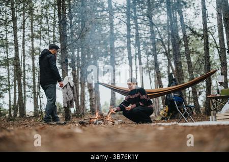 Accogliente raduno di falò in un ambiente boschivo con un'amaca in una bella giornata Foto Stock