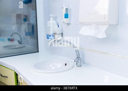 Questa immagine mostra un lavandino elegante ed elegante dotato di elementi essenziali per l'igiene come dispenser di sapone e asciugamani, progettato per la pulizia e la pulizia Foto Stock