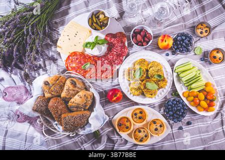 Picnic, antipasti e vassoio di formaggi e carne con muffin dolci e salati e frutta Foto Stock