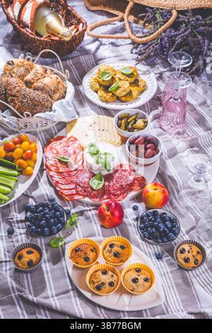 Picnic, antipasti e vassoio di formaggi e carne con muffin dolci e salati e frutta Foto Stock