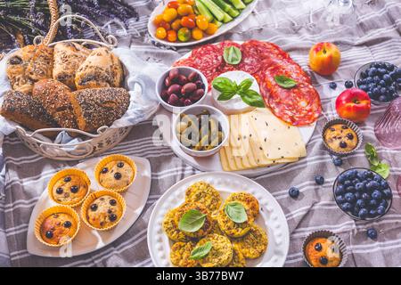 Picnic, antipasti e vassoio di formaggi e carne con muffin dolci e salati e frutta Foto Stock
