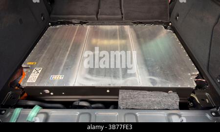 Una batteria per auto elettriche con etichette di avvertenza visibili, simboli di riciclaggio e involucro in metallo. Foto Stock