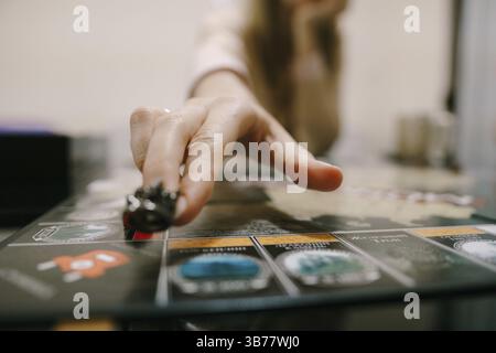 La mano della donna muove figurine nel gioco da tavolo, primo piano. Giochi di home board Foto Stock