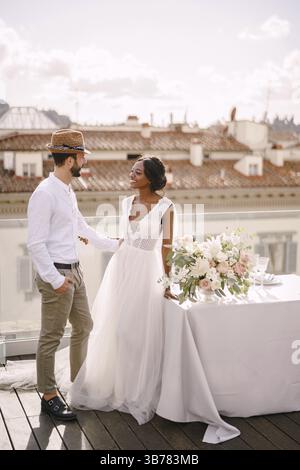 Coppia di nozze interrazziale. Matrimonio a Firenze, Italia. Sposa afroamericana e sposo caucasico con barba e cappello di paglia, ne Foto Stock