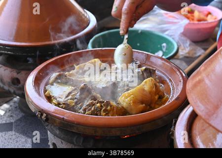 Primo piano di una tajine di pollo, un tipico stufato marocchino di carne speziata e verdure preparato a cottura lenta in un piatto di terracotta poco profondo Foto Stock