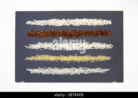 Raccolta del riso su piastra di ardesia. Diversi tipi di riso sulla scrivania in ardesia Foto Stock