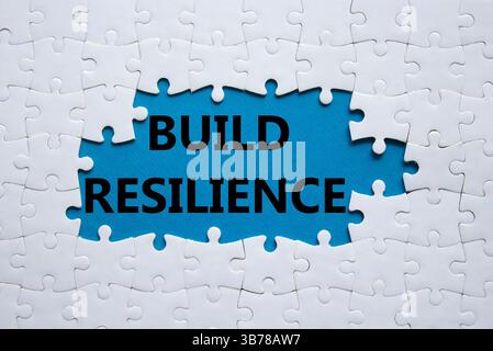Simbolo di resilienza. Puzzle bianco con parole per una maggiore resilienza. Bellissimo sfondo blu. Business e creazione di un concetto di resilienza. Copia spazio. Foto Stock