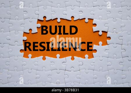 Simbolo di resilienza. Puzzle bianco con parole per una maggiore resilienza. Bellissimo sfondo arancione. Business e creazione di un concetto di resilienza. Copia spazio. Foto Stock