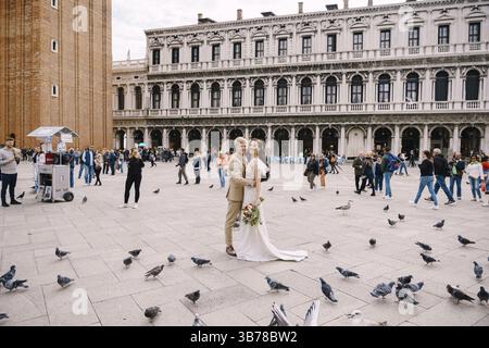 Venezia, Italia - 4 ottobre 2019: Matrimonio a Venezia, Italia. Gli sposi guardano la macchina fotografica tra i piccioni di Piazza San Marco, contro il dorso Foto Stock