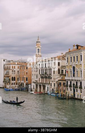 Venezia, Italia - 04 ottobre 2019: Una gondola con i turisti naviga lungo il Canal Grande tra le facciate delle case veneziane che si erigono sull'acqua Foto Stock