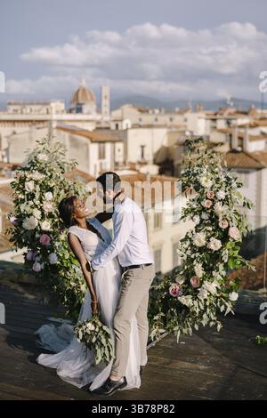Matrimonio multirazziale. Matrimonio a Firenze, Italia. Una cerimonia nuziale sul tetto dell'edificio, con vista sulla città Foto Stock