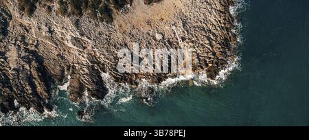 Spettacolare sfondo marino. Costa rocciosa del Mare Adriatico. Onde bianche e spumeggianti battono contro la riva di pietra. Panorama della costa marittima. Vista dall'alto dell'antenna Foto Stock