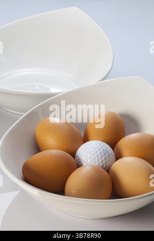 Due ciotole di ceramica bianca, uova di pasqua e palle da golf Foto Stock