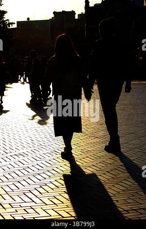 Scene di tutti i giorni in Giappone silhouette di una coppia che cammina attraverso la città alla luce del sole al crepuscolo Foto Stock