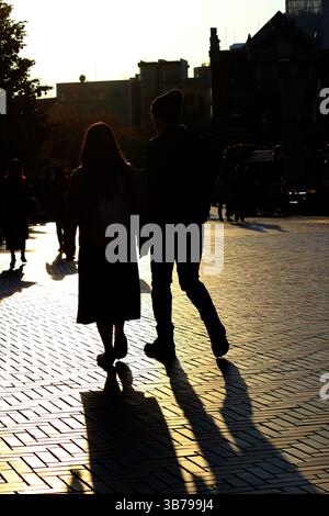 Scene di tutti i giorni in Giappone silhouette di una coppia che cammina attraverso la città alla luce del sole al crepuscolo Foto Stock