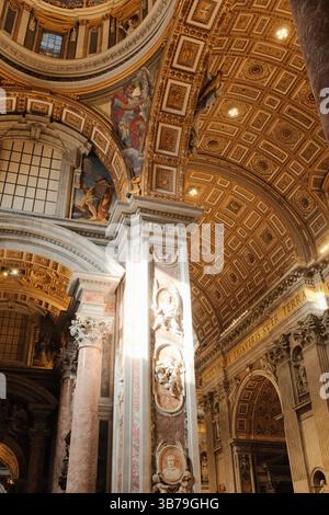 Soffitto decorativo a cassettoni dorati e colonne dettagliate con affreschi e intagli all'interno della basilica di San Pietro che mostrano l'architettura barocca cattolica nella città del Vaticano. Foto di alta qualità Foto Stock