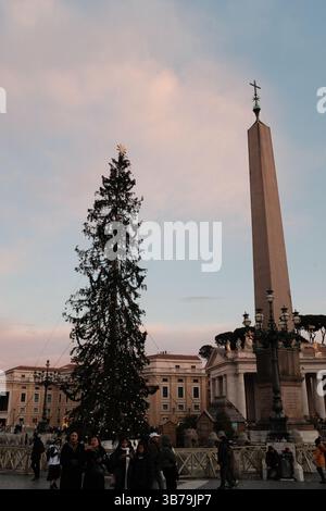 Piazza San Pietro al tramonto durante il periodo natalizio con folle di pellegrini decorati e morbidi cieli pastello intorno ai colonnati della città del Vaticano. Foto di alta qualità Foto Stock