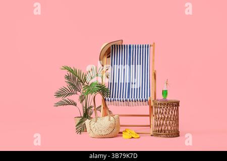 Sdraio a righe con bicchiere di cocktail, borsa da spiaggia e infradito su sfondo rosa Foto Stock