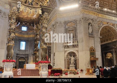 Baldacchino ornato sull'altare papale nella Basilica di San Pietro città del Vaticano progettato da Gian Lorenzo Bernini con colonne in bronzo ritorto decorazioni floreali rosse e iscrizioni latine sotto la grande cupola. Foto di alta qualità Foto Stock