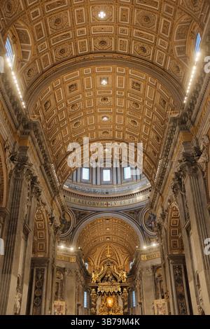 Navata centrale della Basilica di San Pietro decorata per Natale con soffitto a cassettoni dorati pavimenti in marmo e turisti che camminano verso l'altare papale nella città del Vaticano. Foto di alta qualità Foto Stock