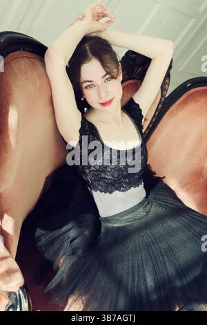 Una giovane ballerina con collant in laccetto e pizzo posa seduta su un divano, ritratto di una ballerina Foto Stock