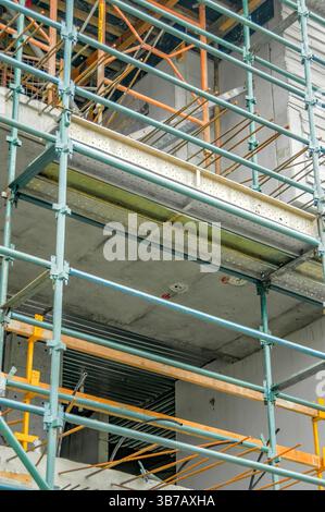 Struttura per ponteggi che circonda un edificio in costruzione, con pavimenti in cemento grezzo e barre di supporto in metallo Foto Stock