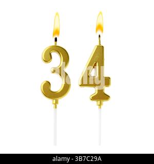 Bruciare candele dorate che compongono il numero 34 su sfondo bianco. Decorazioni festive per il compleanno o altre date speciali Foto Stock