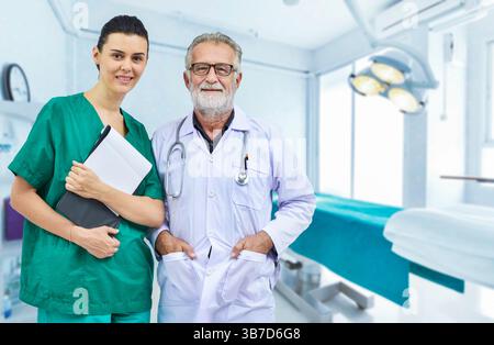 Medico senior e giovane infermiere con cartella paziente sullo sfondo della sala operatoria, concetto di assistenza sanitaria e trattamento medico dei pazienti Foto Stock