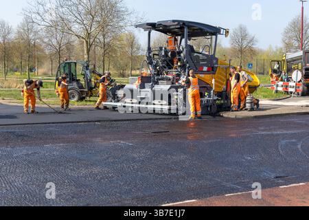 Il personale addetto alla costruzione di strade e i macchinari, compresa un'asfaltatrice, lavorano alla posa di nuovo asfalto su una strada. Utrecht, Paesi Bassi, 11 aprile 2025. Foto Stock