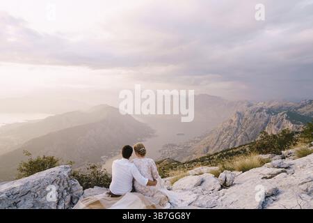 Sposa e sposo siediti sulla montagna e guarda la baia. Foto Stock