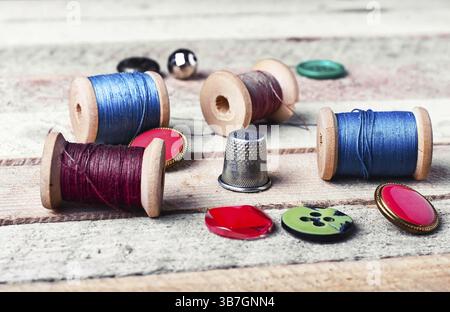 Bobine di filo e vari bottoni su sfondo in legno Foto Stock