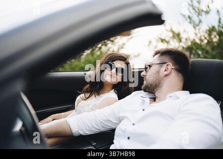 La sposa e lo sposo sono seduti in un'auto aperta sulla pittoresca strada delle montagne del Montenegro . Foto Stock